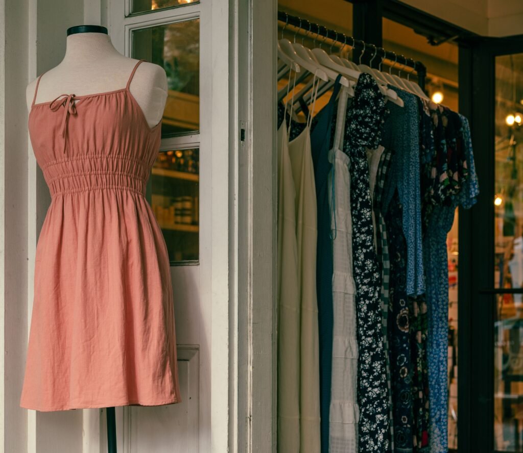 Mannequin with a pink dress and clothing rack in a stylish boutique.